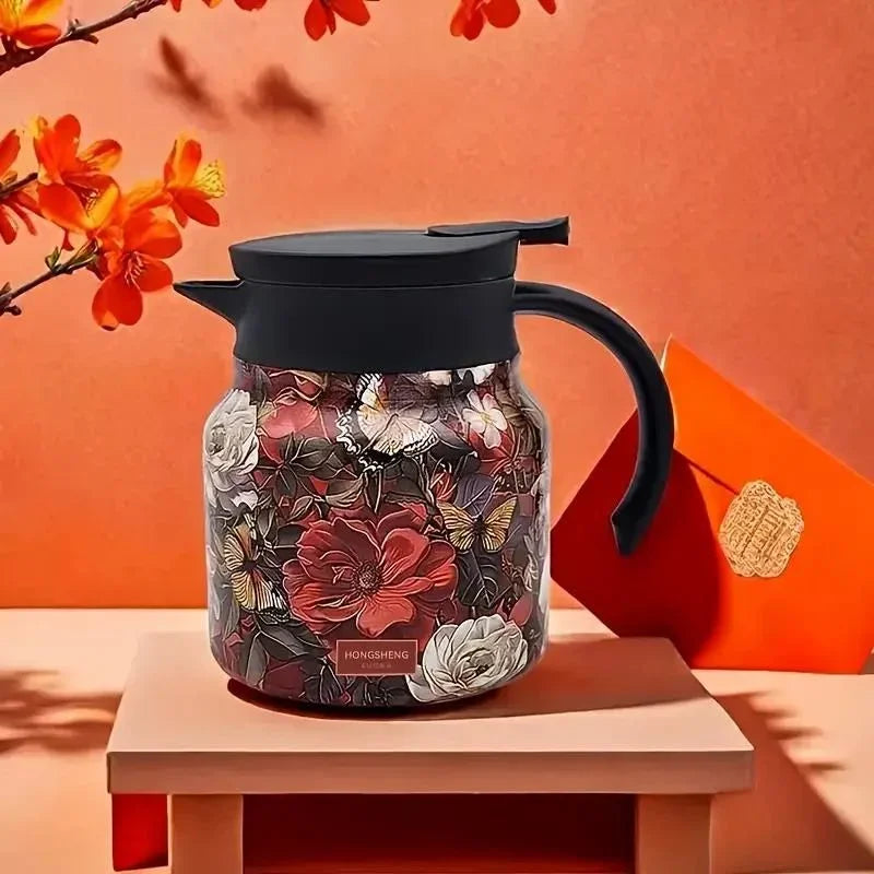 Decorative glass teapot with floral design on a wooden table against an orange background